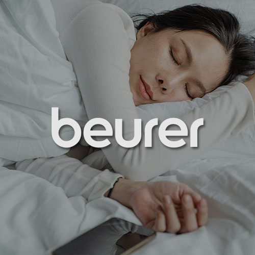 Schlafende Frau in einem Bett. Mittig im Bild wird das beurer Logo dargestellt.